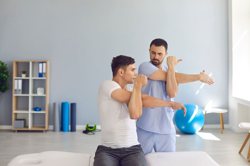fisio haciendo ejercicios de brazos con paciente