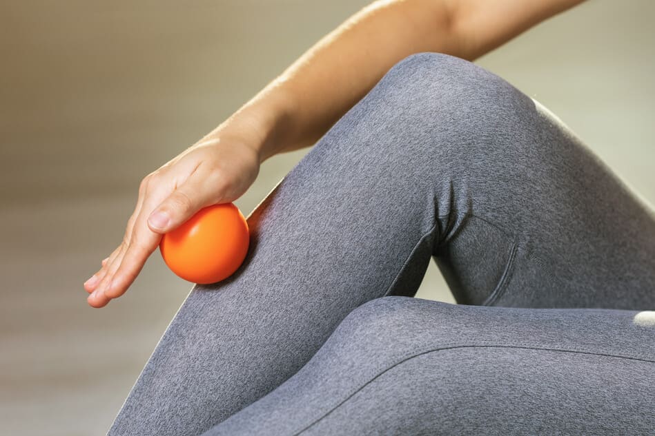 mujer haciendo ejercicios con una pelota sobre la pierna